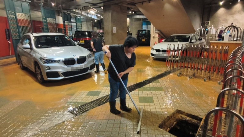 酒店职员慌忙用扫帚扫水。